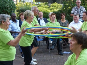 Hermann Gröhe (r.), Hans Sarpei (l.), und Lars Görgens verfolgen Übungen der ZUG-Gruppe im Garten des Hochhauses Florenzer Str. 32